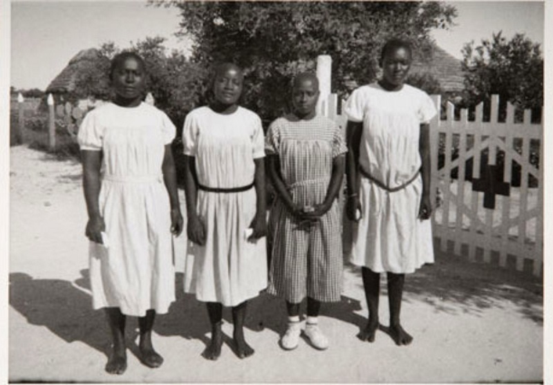 Neljä namibialaista henkilöä vaaleissa mekoissa.